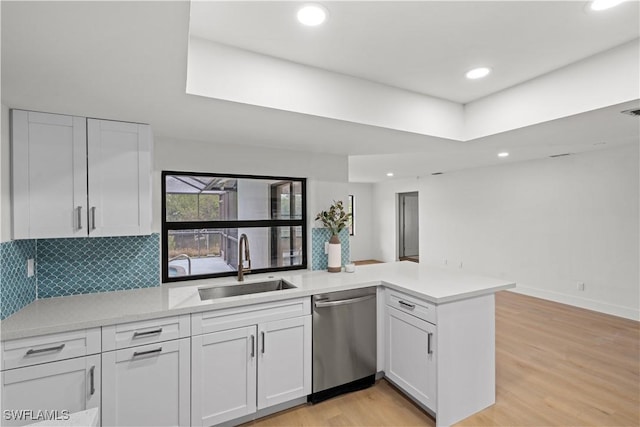 kitchen with light wood-style flooring, white cabinetry, a sink, dishwasher, and a peninsula