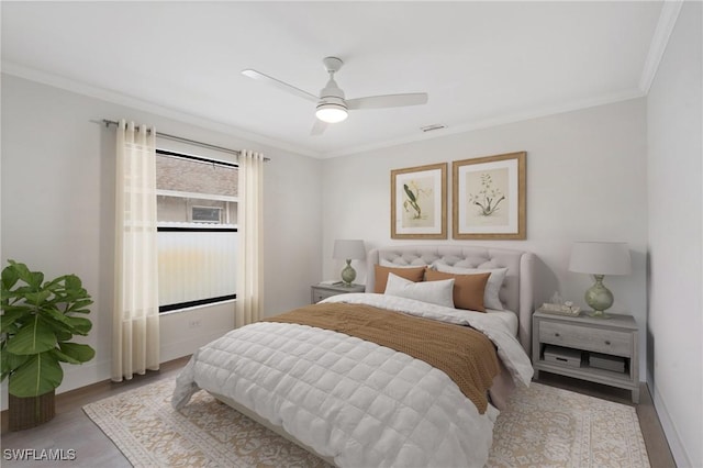 bedroom featuring crown molding, visible vents, a ceiling fan, wood finished floors, and baseboards