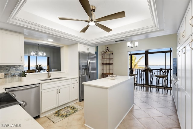 kitchen featuring sink, white cabinetry, a tray ceiling, pendant lighting, and stainless steel appliances