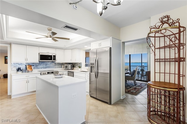 kitchen with sink, tasteful backsplash, a raised ceiling, stainless steel appliances, and white cabinets