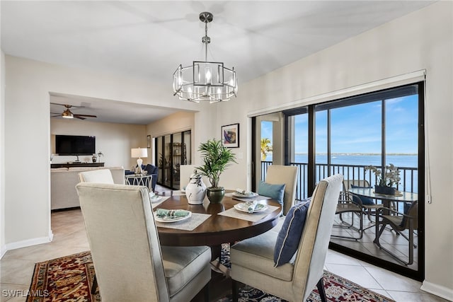 tiled dining space featuring ceiling fan with notable chandelier and a water view