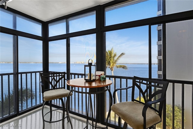 sunroom featuring a water view