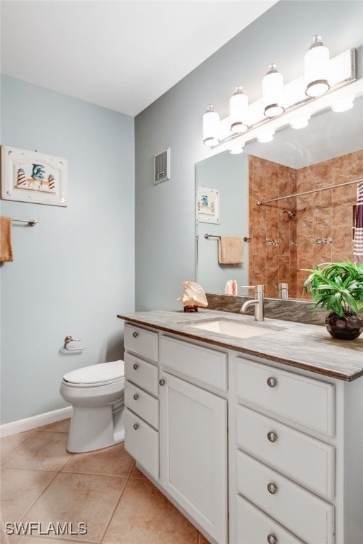 bathroom with tiled shower, vanity, toilet, and tile patterned flooring