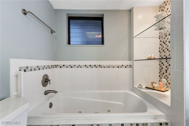 bathroom featuring tiled tub and toilet