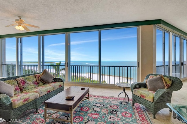 living room featuring a textured ceiling, a water view, and ceiling fan