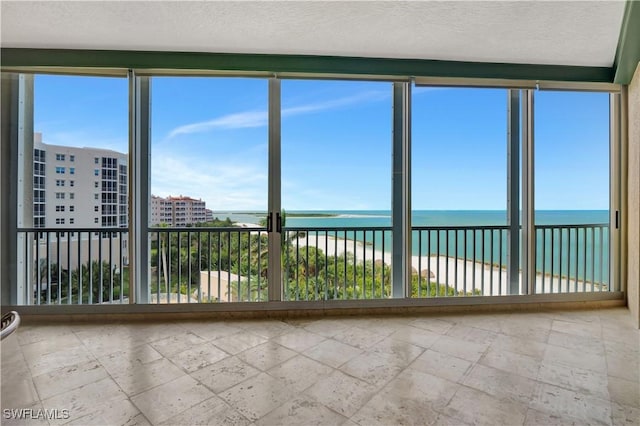 unfurnished sunroom with a water view and a beach view