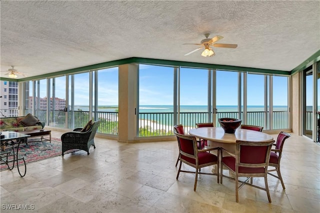 sunroom / solarium featuring ceiling fan and a water view