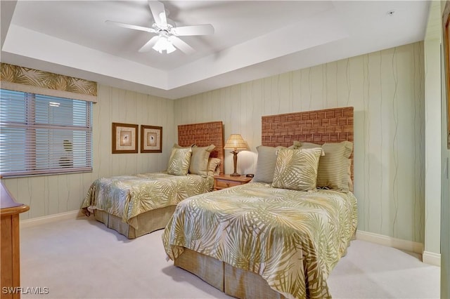 bedroom featuring light carpet, ceiling fan, and a raised ceiling