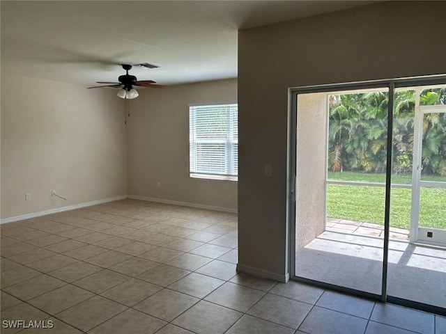 tiled spare room with a ceiling fan, visible vents, and baseboards