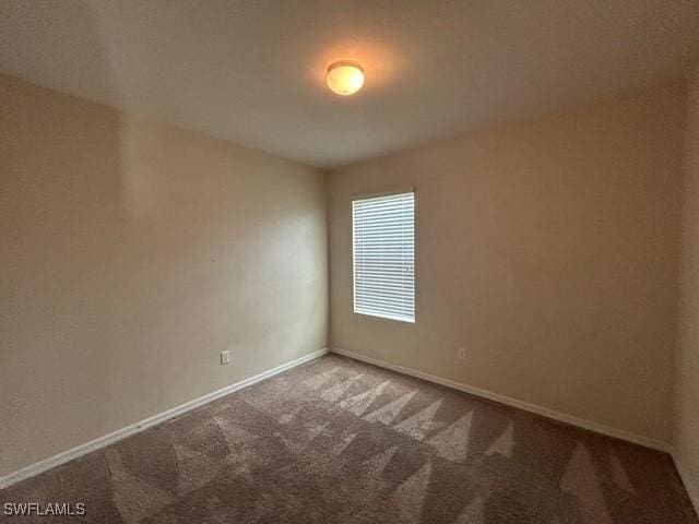 unfurnished room featuring carpet and baseboards