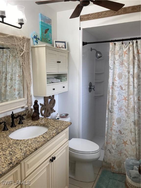 bathroom featuring tile patterned floors, toilet, vanity, curtained shower, and ceiling fan