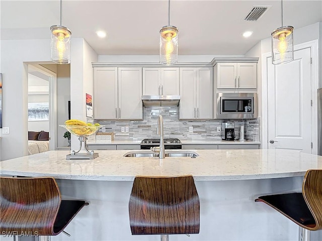 kitchen with stainless steel microwave, decorative light fixtures, and a breakfast bar area