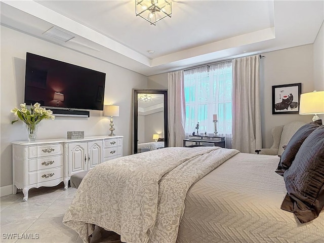 bedroom featuring light tile patterned flooring and a tray ceiling