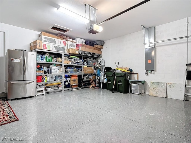 garage with a garage door opener, stainless steel fridge, and electric panel