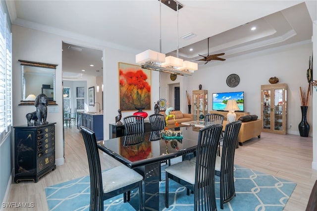 dining space featuring ceiling fan, ornamental molding, sink, and light hardwood / wood-style flooring