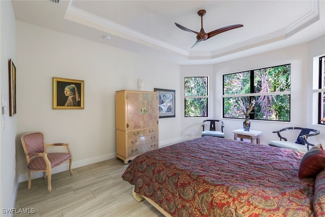 bedroom with ceiling fan, ornamental molding, a tray ceiling, and light hardwood / wood-style floors