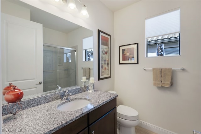 bathroom featuring vanity, toilet, and a shower with shower door