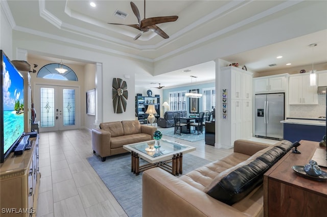 tiled living room featuring french doors, ceiling fan, a tray ceiling, and crown molding