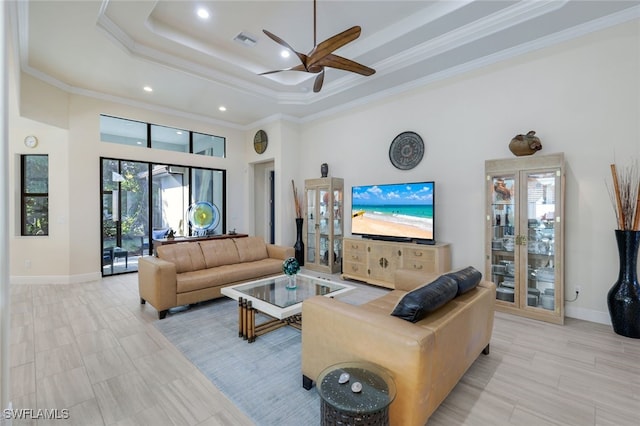 living room with ceiling fan, a towering ceiling, ornamental molding, and a tray ceiling