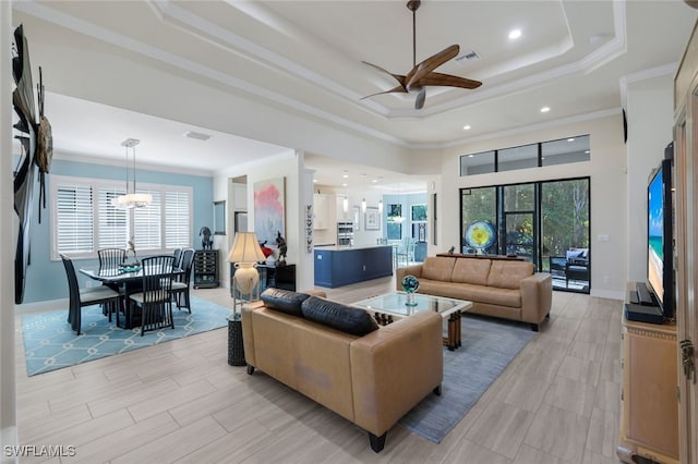 living room featuring ornamental molding, plenty of natural light, ceiling fan, and a tray ceiling