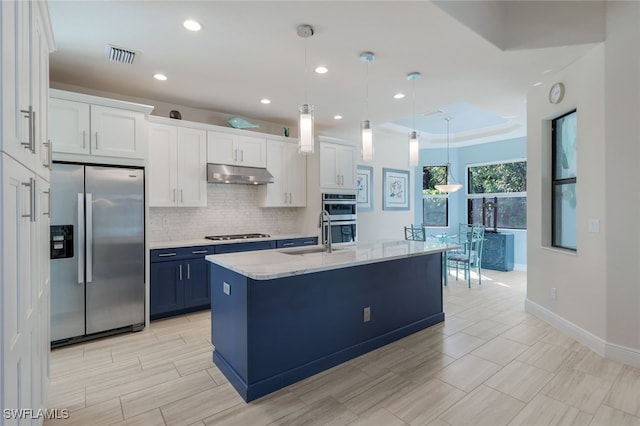 kitchen featuring sink, white cabinets, hanging light fixtures, stainless steel appliances, and a center island with sink