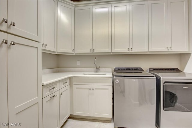 washroom featuring cabinets, washing machine and clothes dryer, and sink