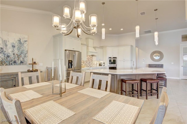 dining room with an inviting chandelier, ornamental molding, and sink