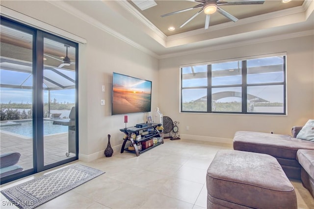 tiled living room with crown molding, ceiling fan, a healthy amount of sunlight, and a tray ceiling