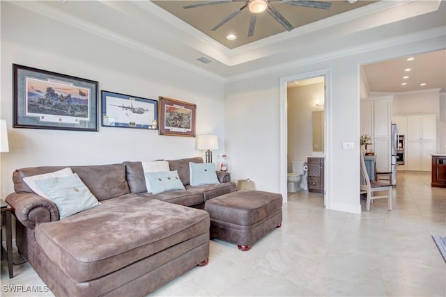 living room featuring ceiling fan, ornamental molding, and a tray ceiling