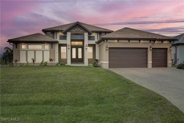 prairie-style home featuring french doors, a garage, and a lawn