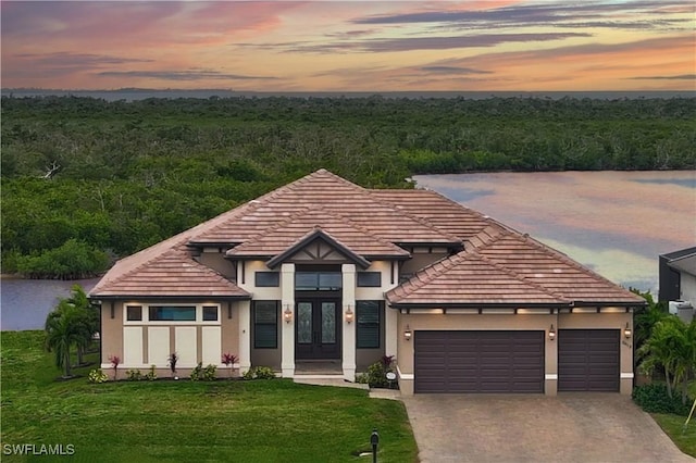 view of front of property with french doors, a garage, and a lawn