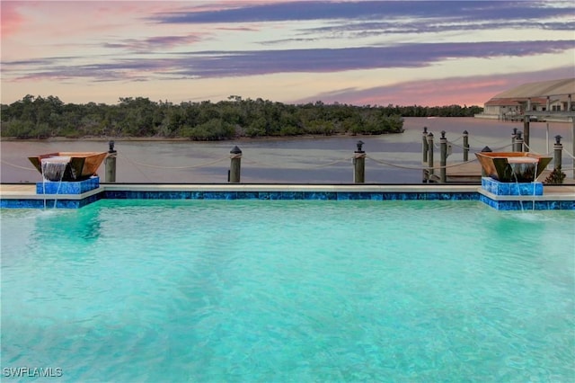 pool at dusk featuring pool water feature