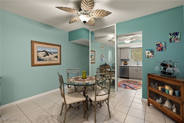 dining space with light tile patterned flooring, ceiling fan, sink, and a textured ceiling