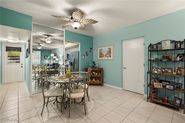 tiled dining space with a textured ceiling and ceiling fan