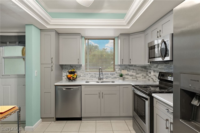 kitchen featuring stainless steel appliances, sink, light tile patterned floors, and a tray ceiling