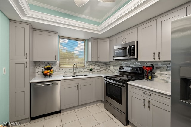 kitchen featuring sink, gray cabinetry, light tile patterned floors, a raised ceiling, and stainless steel appliances