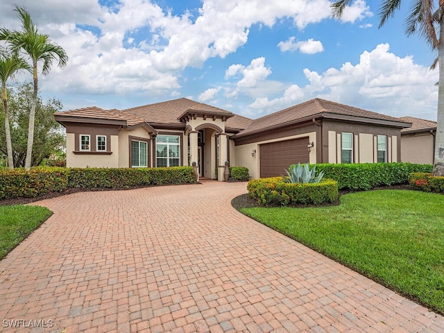 mediterranean / spanish-style house with a garage and a front lawn