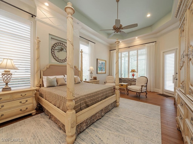 bedroom with hardwood / wood-style flooring, ceiling fan, and a tray ceiling