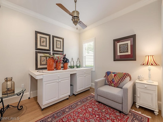 living area with crown molding, built in desk, ceiling fan, and light hardwood / wood-style flooring