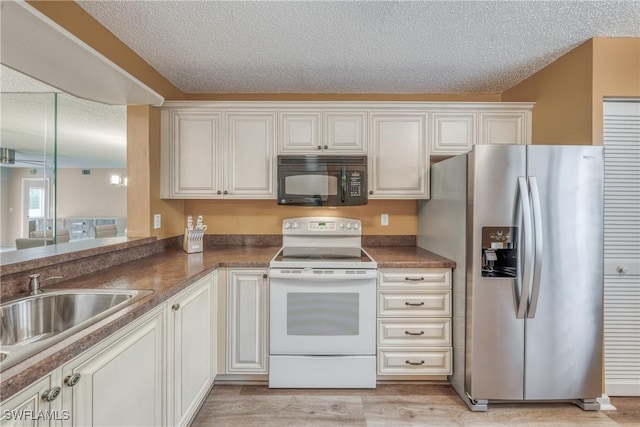 kitchen with dark countertops, electric range, white cabinets, black microwave, and stainless steel fridge