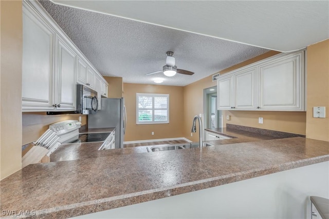 kitchen featuring appliances with stainless steel finishes, white cabinets, a sink, ceiling fan, and a peninsula