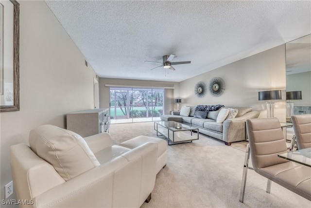 living room with light carpet, ceiling fan, and a textured ceiling