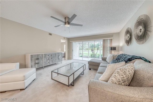 living room featuring a textured ceiling, visible vents, a ceiling fan, and light colored carpet