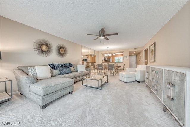 living area with visible vents, carpet flooring, vaulted ceiling, a textured ceiling, and ceiling fan with notable chandelier