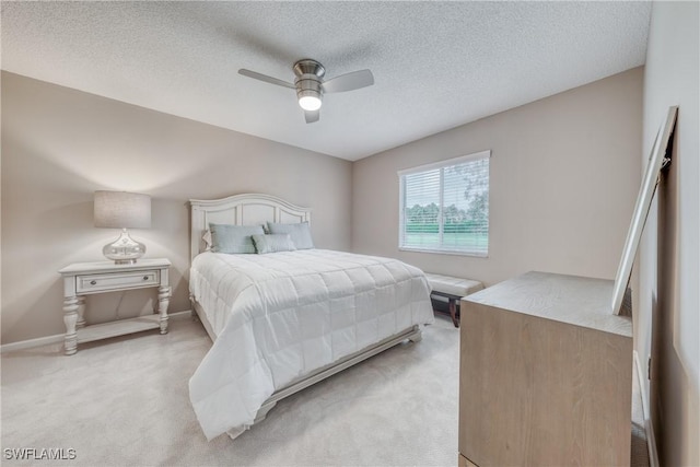 bedroom featuring light carpet, ceiling fan, baseboards, and a textured ceiling