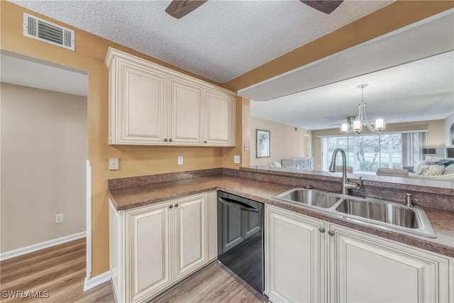 kitchen featuring a sink, visible vents, open floor plan, dishwasher, and dark countertops