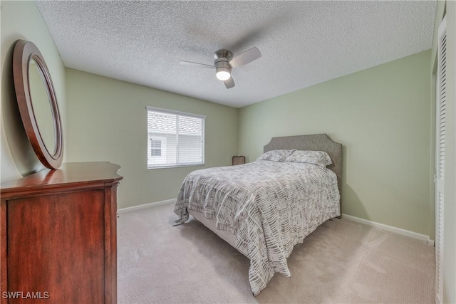 bedroom with a ceiling fan, light carpet, a textured ceiling, and baseboards