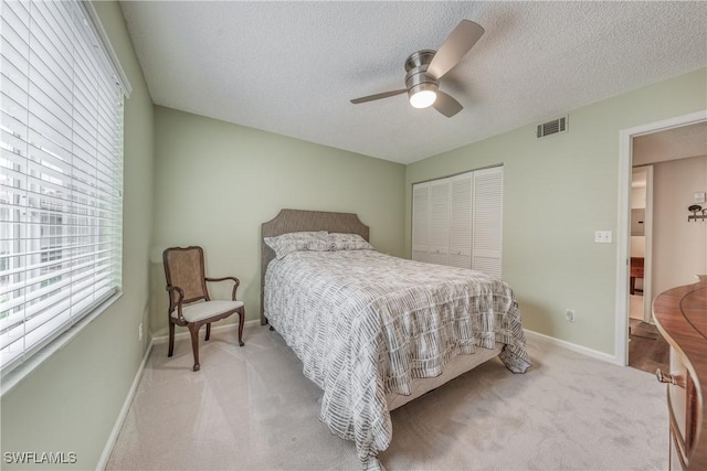 bedroom with light carpet, a closet, a textured ceiling, and visible vents