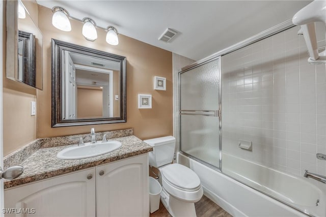 full bath with toilet, visible vents, bath / shower combo with glass door, and vanity