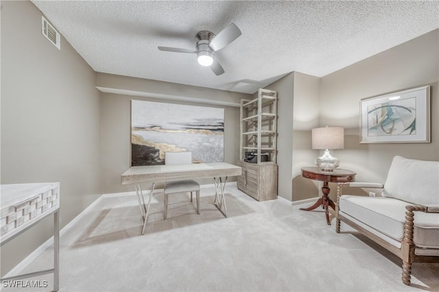 office area with baseboards, visible vents, a ceiling fan, light colored carpet, and a textured ceiling